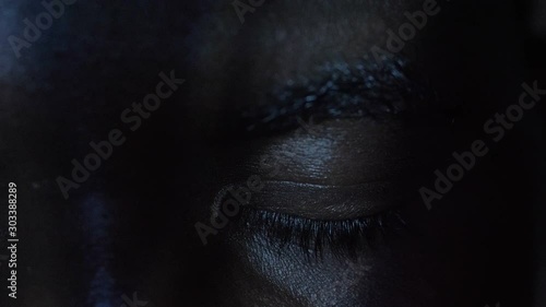 angry young black man opening his closed eyes in the dark,staring at camera photo