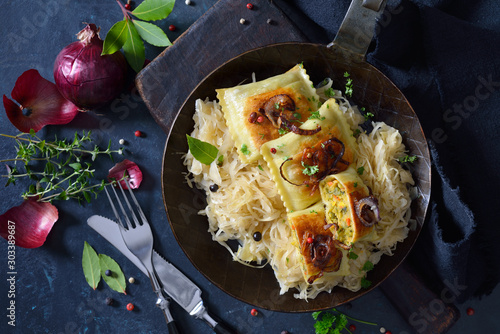 Gebratene schwäbische Gemüse-Maultaschen mit Röstzwiebeln auf Sauerkraut im Eisenpfandl  serviert - Fried Swabian vegetable ravioli with roasted onions served on sauerkraut in an iron frying pan photo