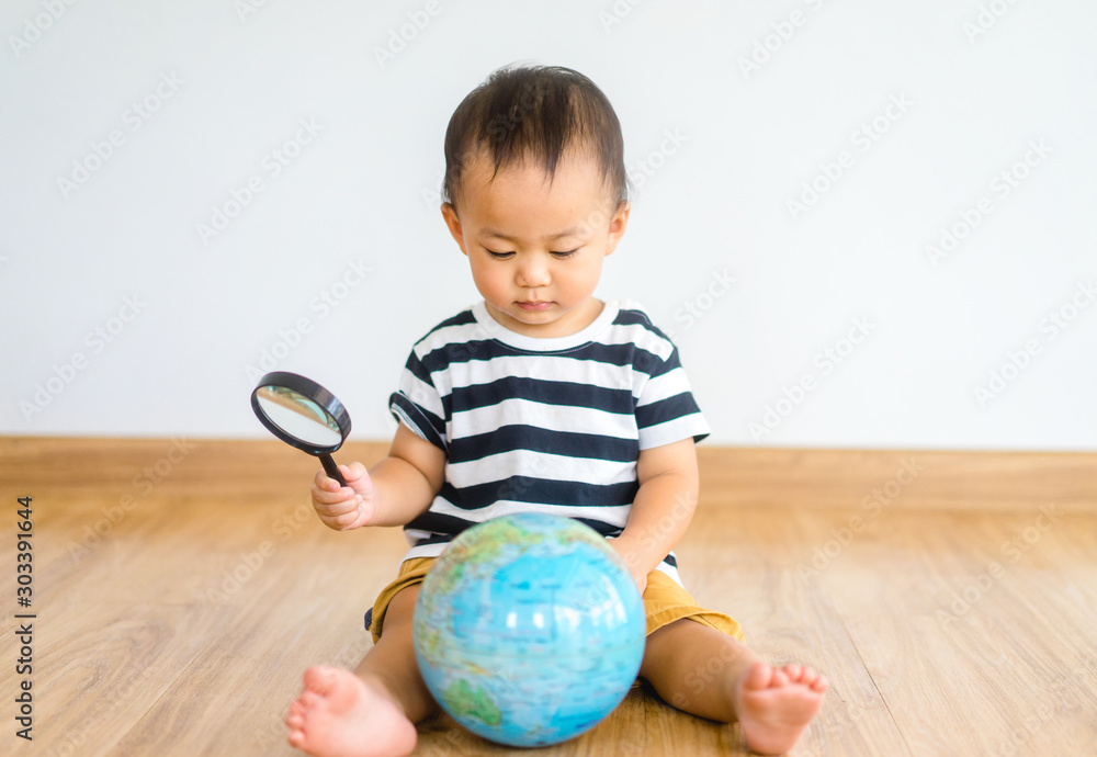 Φωτογραφία Asian chinese baby boy Looking At Globe Through Magnifying Glass at home on white Background