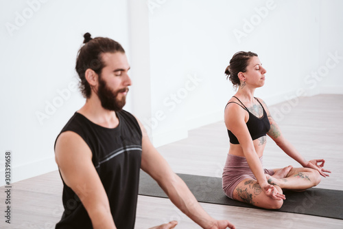 young man and woman practicing yoga sport at the gym. Healthy lifestyle