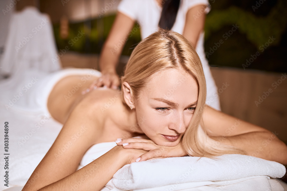 Fototapeta premium Side shot of pretty attractive female having aroma therapy massage with essential oil, looking away with relaxation, health beauty resort relaxation, close up