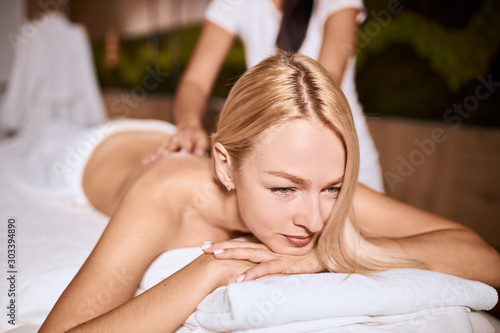 Side shot of pretty attractive female having aroma therapy massage with essential oil, looking away with relaxation, health beauty resort relaxation, close up