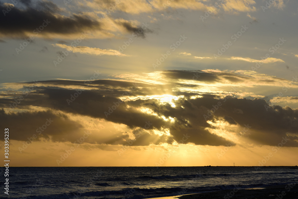 Dramatic sunset in front of cloudy sky at the sea at the coast with water and waves as background