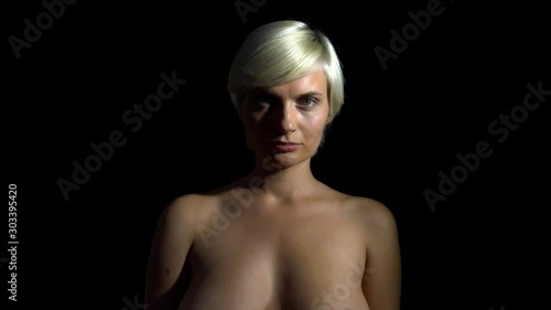 topless blonde lady in dark cover her face, still medium close up shot photo