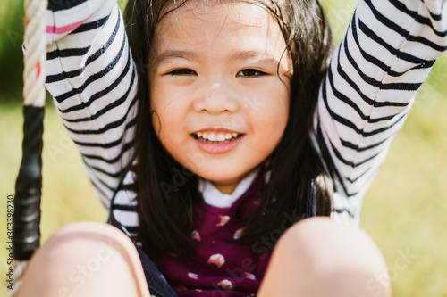 Asian child girl playing on playground in outdoor park.Happy Little asian girl playing swing with her mother.Happy moment and good emotion.