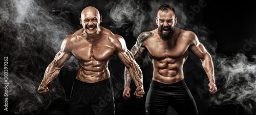 Sport and fitness concept. Two wild sportsmen boxers and bodybuilders posing on black background with smoke before competition or fight. Copy Space.