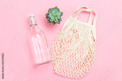 Reusable bottle and reusable mesh bag on pink background. Sustainable lifestyle. Succulents plants
