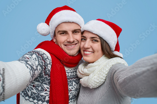 Happy couple in Santa hats smiling and looking at camera