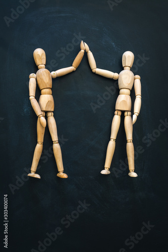 Two wooden people greet each other