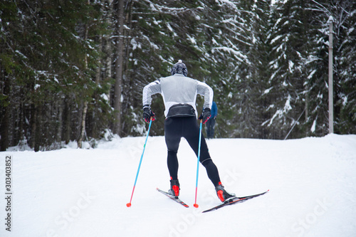 Cross country. A skier is skiing in winter in the woods.