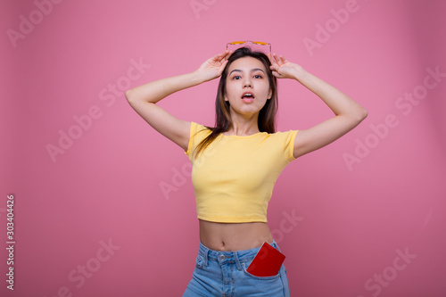 Beautiful portrait young asian woman wear sunglasses on head smile confident enjoy summer holiday isolated blue background, model girl fashion hipster holding passport, travel concept.