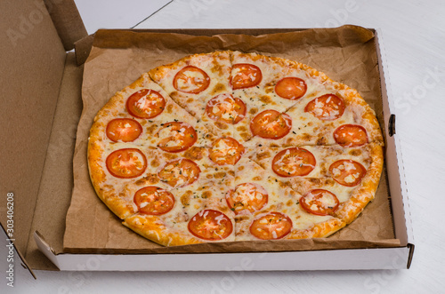 Pizza with cheese and tomatoes on a white wooden background. For menus and advertising pizzerias