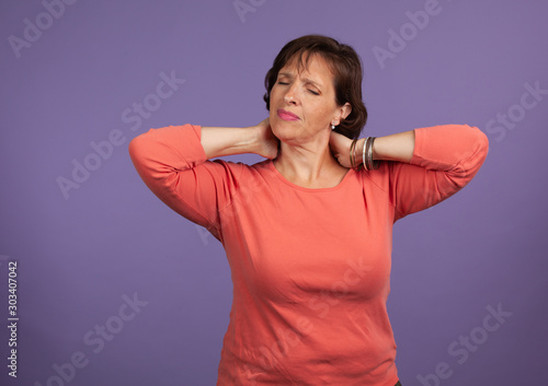 Middle Aged woman with neck and shoulder pain holding her neck  and making a pained expression.