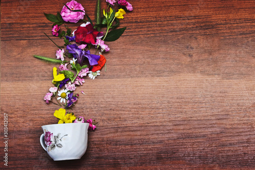 Beautiful frame on a wooden background. Flowers with a cup of tea close-up.