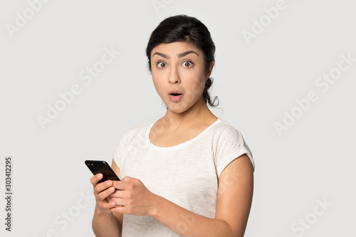 Head shot portrait surprised Indian girl using phone
