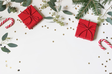 Christmas floral frame, web banner. Fir, berry eucalyptus tree branches, red gift boxes, red gift boxes and golden confetti stars isolated on white table background. Winter decoration. Flat lay, top.