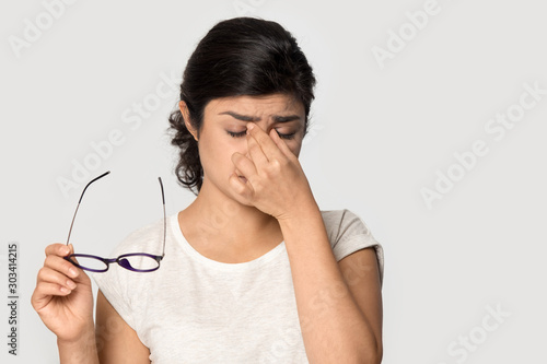 Tired Indian girl taking off glasses, feeling eye strain