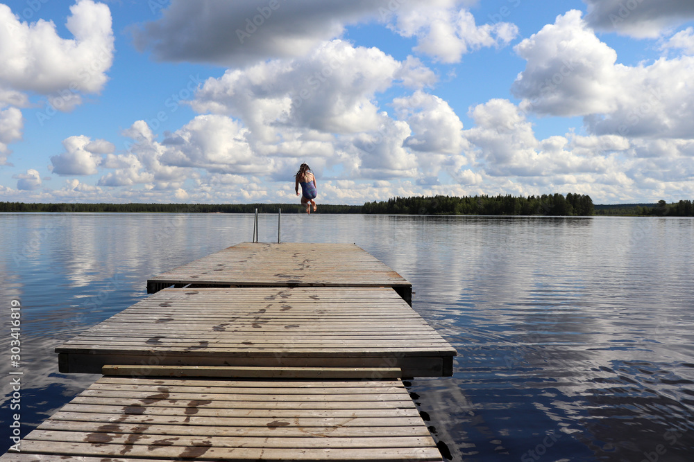 Girl jumping into the water at a lake in Finland