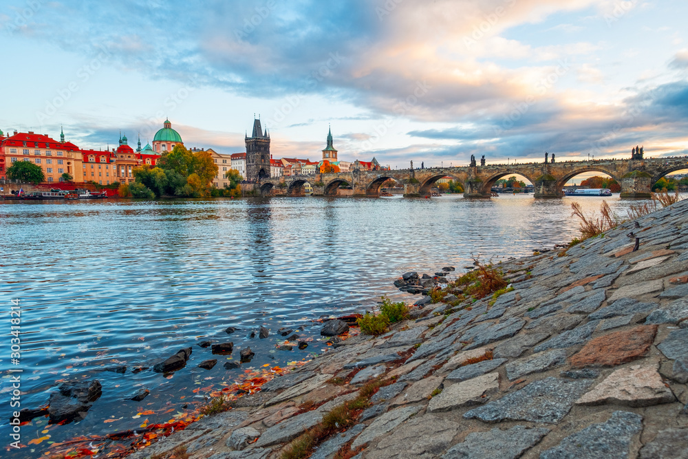 Obraz premium Beautiful view of Old Town buildings and Charles Bridge along the Vltava river at sunset in Prague