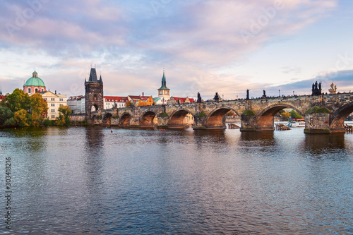 Beautiful view of Old Town buildings and Charles Bridge along the Vltava river at sunset in Prague © rolandbarat