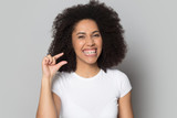 Head shot smiling African American girl showing little size gesture