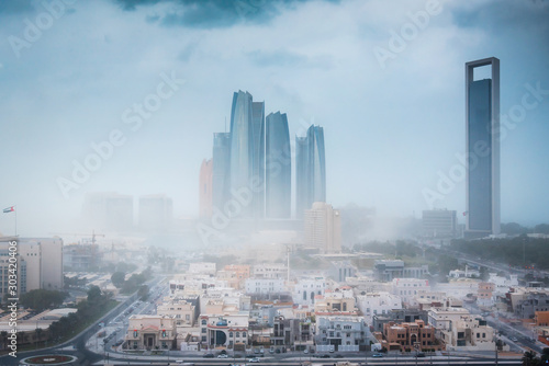 Abu Dhabi during sandstorm and strong wings. View of the UAE capital downtown buildings under strong winds