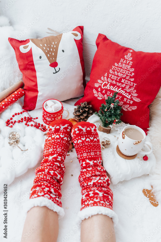 Φωτογραφία Woman in socks on White Christmas background with cups of cocoa drink and  christmas presents