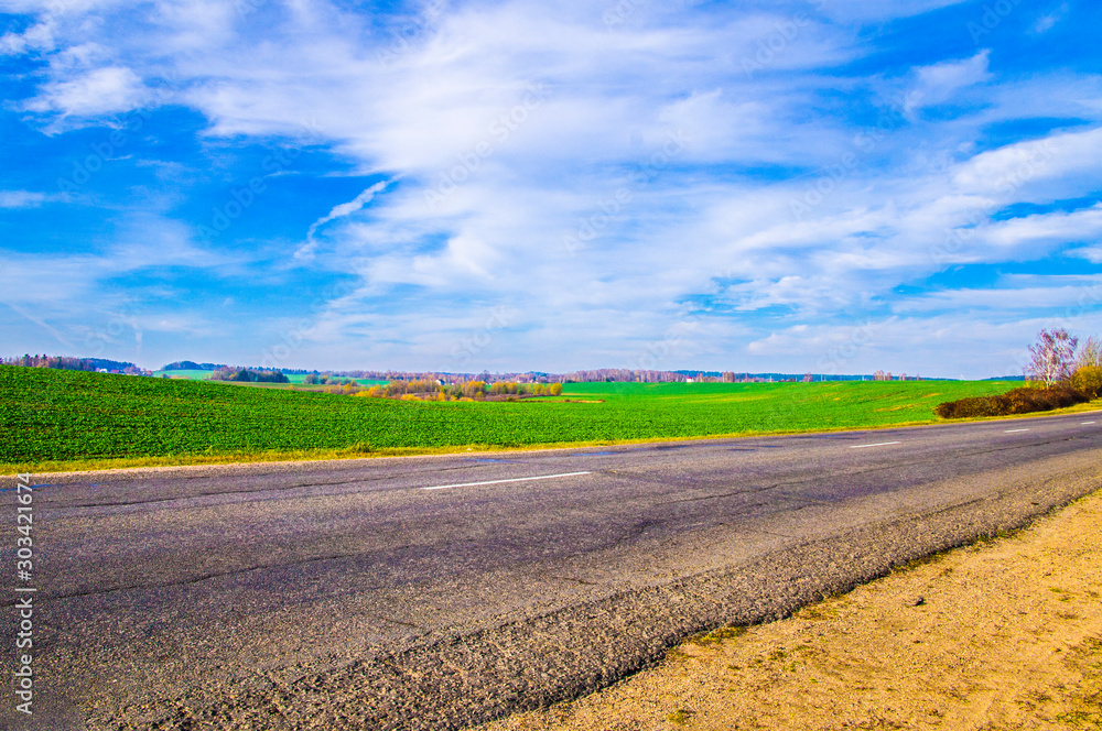 Asphalt road near the field with blue sky. Asphalt road near the field with blue sky.
