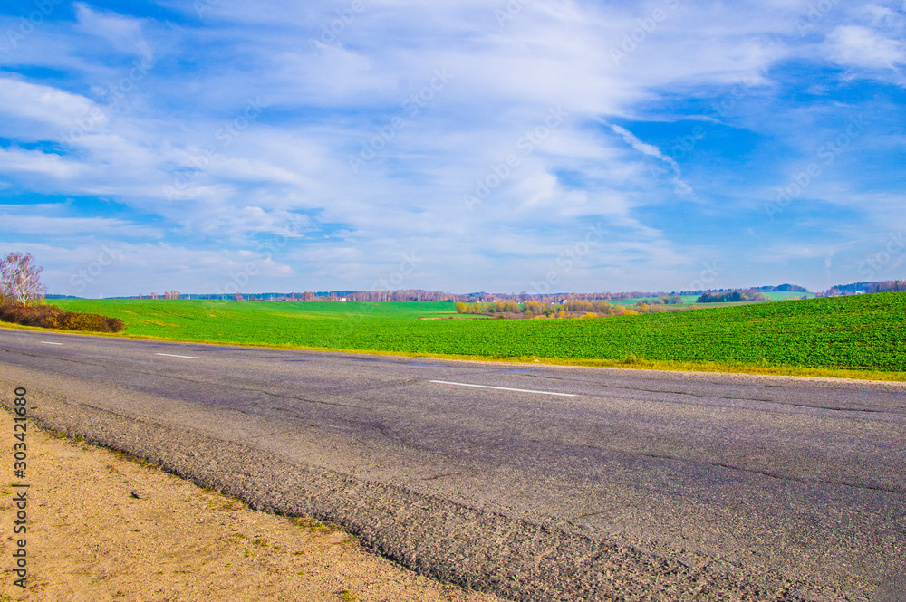 Asphalt road near the field with blue sky.