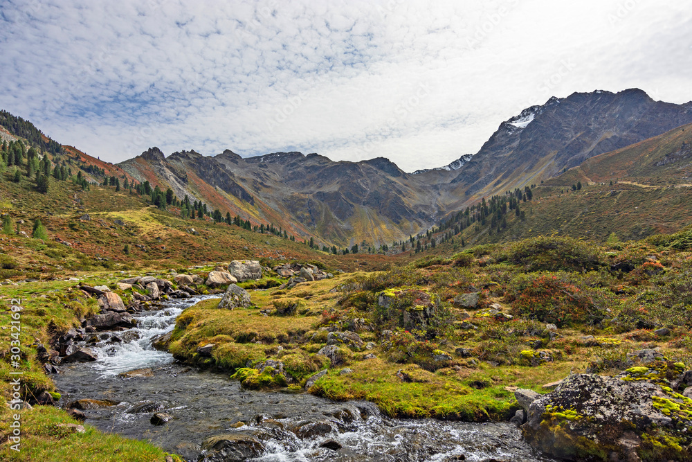 Alpine scenery with a creek, rocky mountains and colorful vegetation in autumn. Ötztal Alps, Tirol, Austria. Alpine scenery with a creek, rocky mountains and colorful vegetation in autumn. Ötztal Alps, Tirol, Austria.