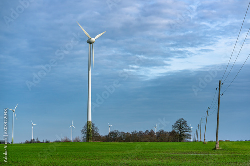 Turbine Green Energy Electricity Technology Concept. Wind farms and wooden electric poles standing on the field