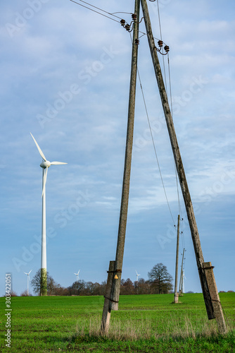 Turbine Green Energy Electricity Technology Concept. Wind farms and wooden electric poles standing on the field