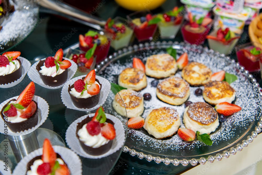 Cheesecakes with sour cream, mint, strawberries on a breakfast buffet Cheesecakes with sour cream, mint, strawberries on a breakfast buffet