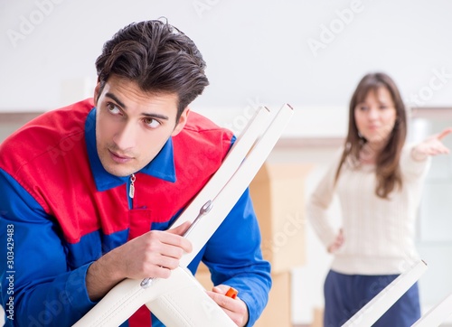 Contractor repairman assembling furniture under woman supervisio photo