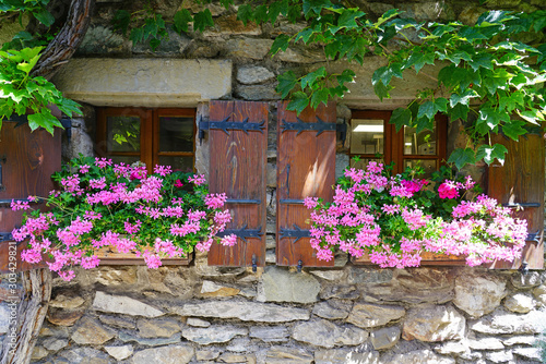 View of a window with shutters with colorful flower windowboxes photo