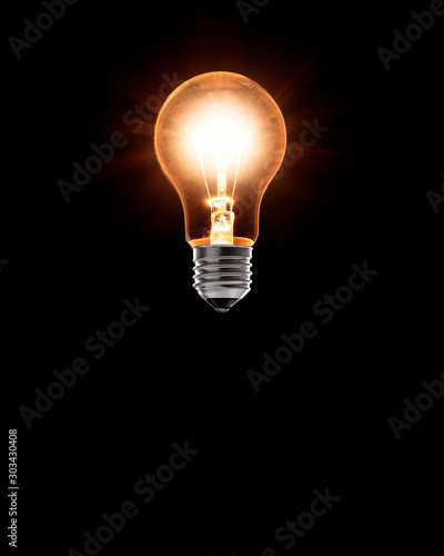 Burning classical light bulb levitating in the air. Black background