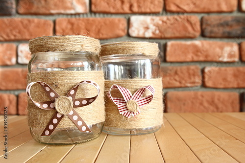 DIY Home decor - decorated jars with natural string with a bow on the background of a brick wall © Cezzar