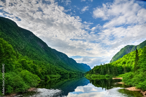 Vibrant green forest and still waters of Jacques Cartier river on a warm summer day, Jacques cartier national park, Quebec, Canada