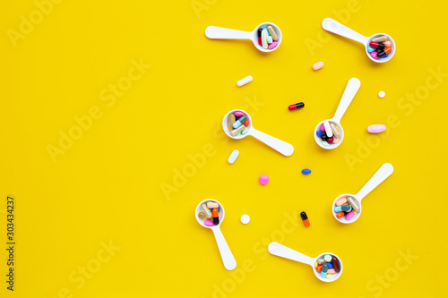 Colorful tablets with capsules and pills on yellow background.
