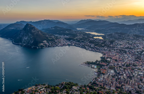 Aerial drone shot view before sunset of Swiss city Lugano and Monte Salvatore by Lago di lugano © Davidzfr