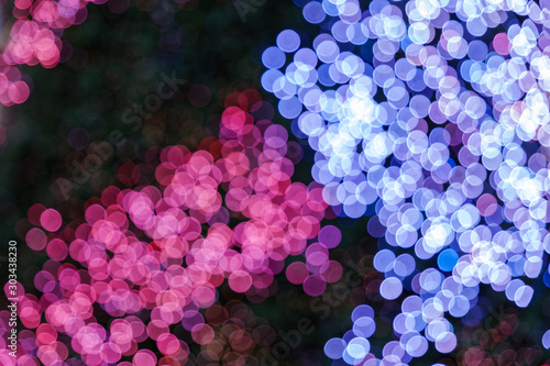 Fototapeta Naklejka Na Ścianę i Meble -  Illuminated abstract round red, purple, blue and magenta bokeh on dark background. Colourful glitter bokeh from out of focus view of decoration bulbs.