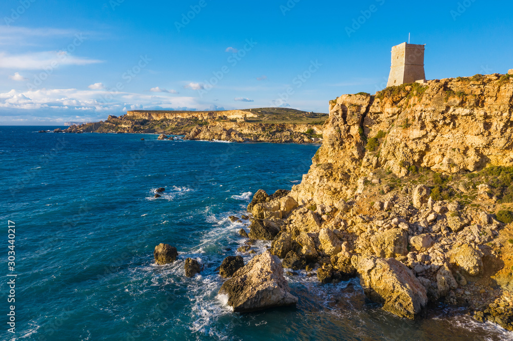 Ghajn Tuffieha Tower. Aerial view from the sea, sunset time. Blue sky. Malta