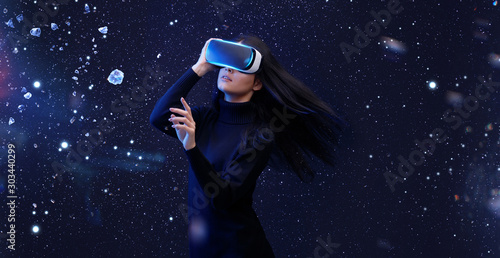 Beautiful woman with flowing hair in futuristic dress over dark background. Girl in glasses of virtual reality. Augmented reality, game, future technology concept. VR.