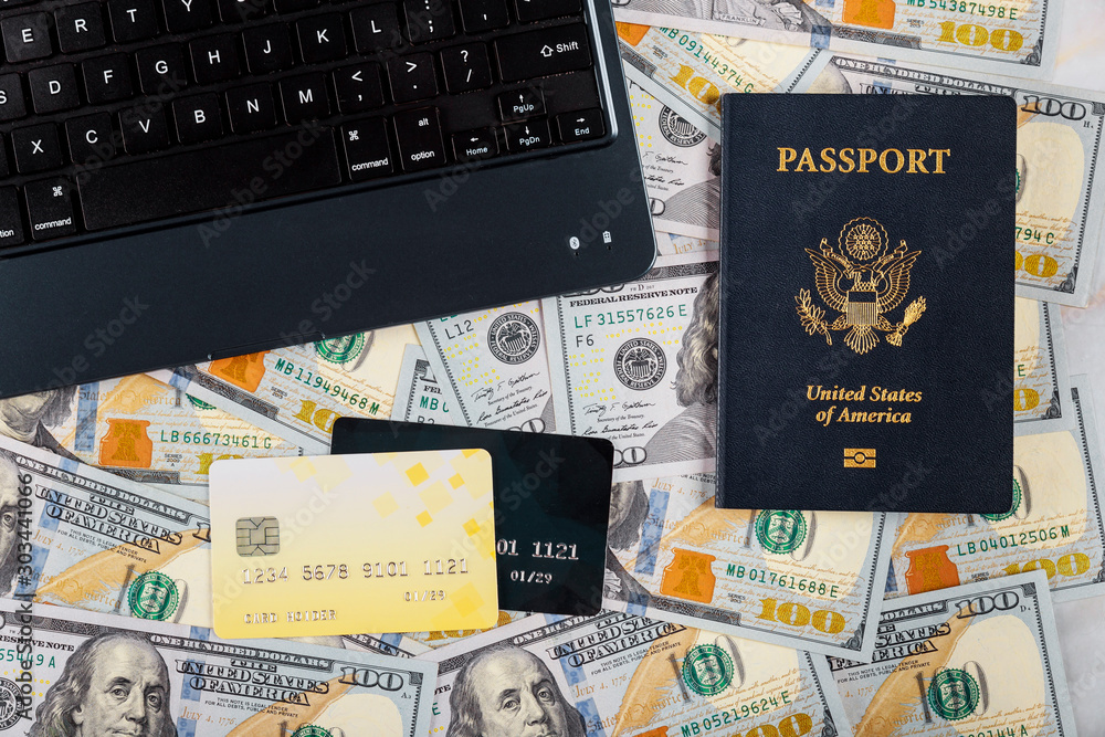 Naklejka premium Technology and internet computer keyboard, hundred US dollar bills on buying a ticket online with credit card on American passport