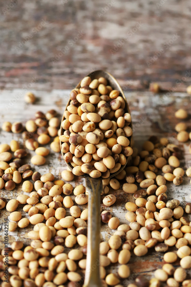 Soybeans in a spoon and sprinkled on a wooden surface. Organic soybeans. Soybeans in a spoon and sprinkled on a wooden surface. Organic soybeans.