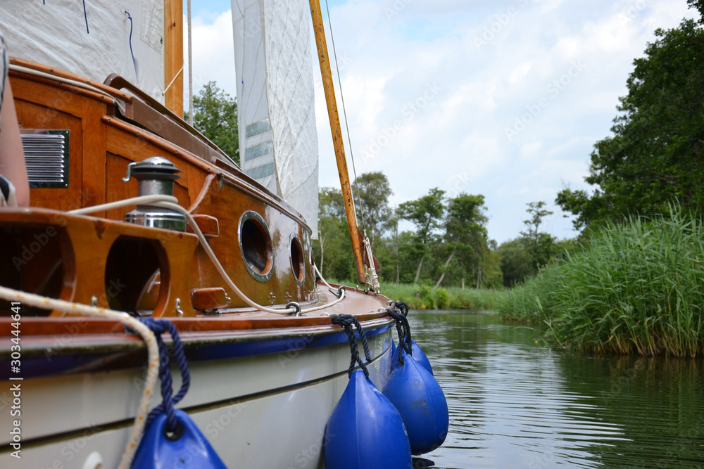 Valokuva Traditional wooden sailing yacht drifting up a wooded, reed lined river