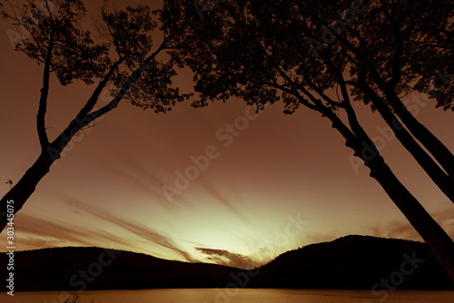 Silhouetted trees framing sunset over a lake in National Park