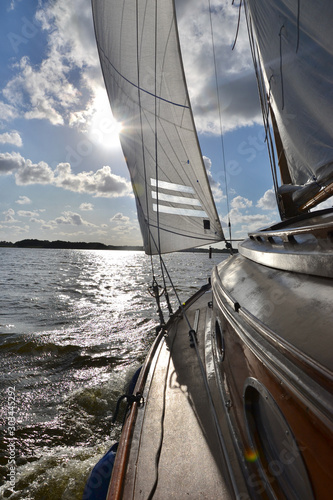 Traditional wooden yacht sailing towards the sun photo