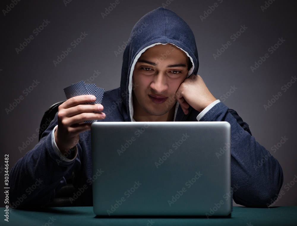 Young man wearing a hoodie sitting in front of a laptop computer Young man wearing a hoodie sitting in front of a laptop computer
