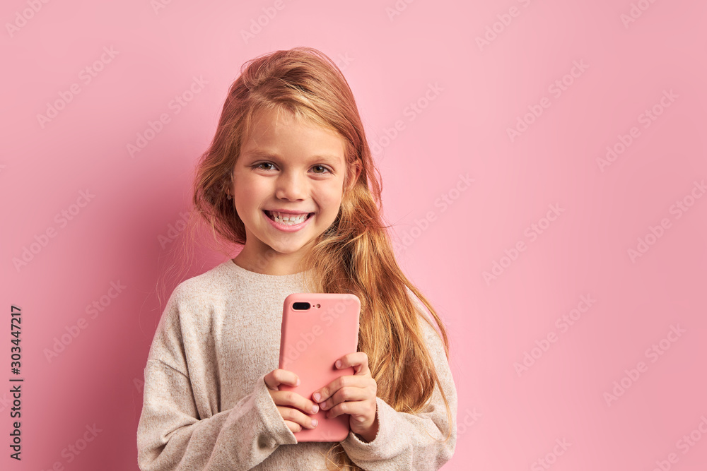 Portrair of smiling open-minded girl in white blouse using smartphone isolated over pink background. Modern technologies nowadays, digital device concept Portrair of smiling open-minded girl in white blouse using smartphone isolated over pink background. Modern technologies nowadays, digital device concept